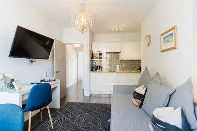 a living room with a blue couch and a kitchen at Design Suites Lytham in Lytham St Annes
