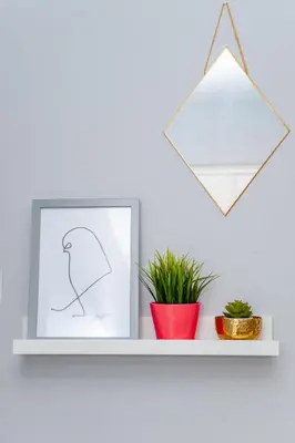 a shelf with a picture and a plant on it at Design Suites Lytham in Lytham St Annes