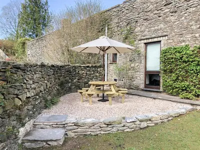 a picnic table and an umbrella in front of a stone building at Yew Tree Farm in High Newton