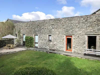 a stone building with a yard and a bench at Yew Tree Farm in High Newton