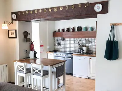 a kitchen with white cabinets and a wooden table at Yew Tree Farm in High Newton