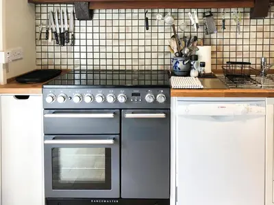 a kitchen with a stainless steel stove and white cabinets at Yew Tree Farm in High Newton