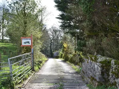 a dirt road with a sign next to a fence at Lakeland View in Scotforth