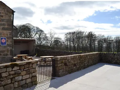 a stone retaining wall with a fence and tables at Lakeland View in Scotforth