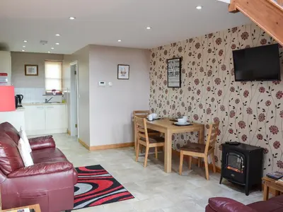 a living room with a couch and a table and a television at Lakeland View in Scotforth
