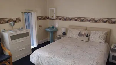 a bedroom with a white bed and a sink at The Kathrene Holiday Flats in Fleetwood