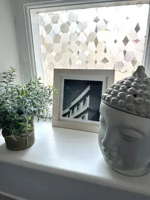 a window sill with a picture of a head and two plants at HomeStay In The Bay By The Beach in Heysham