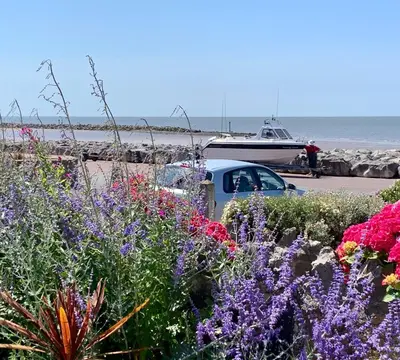 a car parked next to the beach with flowers at HomeStay In The Bay By The Beach in Heysham