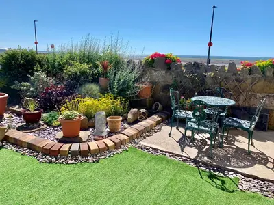 a garden with a table and chairs and plants at HomeStay In The Bay By The Beach in Heysham
