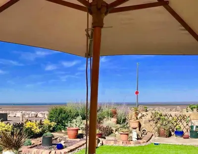 a view from a patio with an umbrella at HomeStay In The Bay By The Beach in Heysham