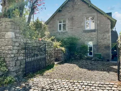 an old stone house with a stone fence at Underhill Cottage in Arnside