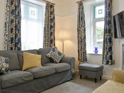 a living room with a couch and two windows at Underhill Cottage in Arnside