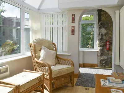 a living room with a chair and windows at Underhill Cottage in Arnside