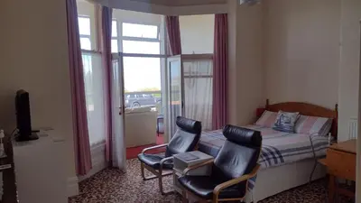 a bedroom with a bed and two chairs and a window at The Kathrene in Fleetwood