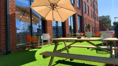 a wooden picnic table with an umbrella on a lawn at Holiday Inn Express - Barrow-in-Furness & South Lakes by IHG in Barrow in Furness