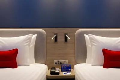two beds with red pillows in a hotel room at Holiday Inn Express - Barrow-in-Furness & South Lakes by IHG in Barrow in Furness