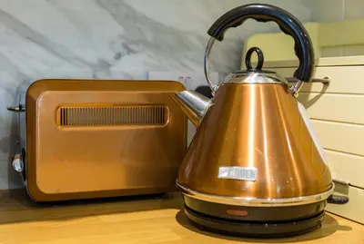 a copper tea kettle sitting next to a toaster at Hampsfell Cottage, quaint and comfy by the Lake District in Grange Over Sands