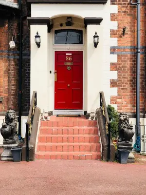 a red door on a brick building with stairs at Castle Lodge Guest House 86-88 Sheil Rd L6 3AF in Liverpool
