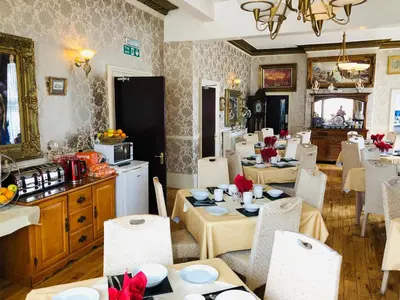 a dining room with tables and chairs and a kitchen at Castle Lodge Guest House 86-88 Sheil Rd L6 3AF in Liverpool