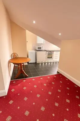 a kitchen with a table and a red rug at Castle Lodge Guest House 86-88 Sheil Rd L6 3AF in Liverpool