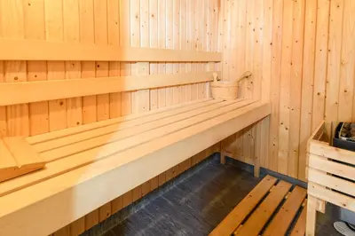 a wooden sauna with a bucket sitting on a bench at Woodlands Hotel & Pine Lodges in Grange Over Sands