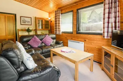 a living room with leather couches and a coffee table at Woodlands Hotel & Pine Lodges in Grange Over Sands