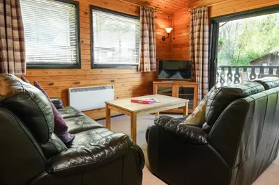 a living room with two leather couches and a table at Woodlands Hotel & Pine Lodges in Grange Over Sands