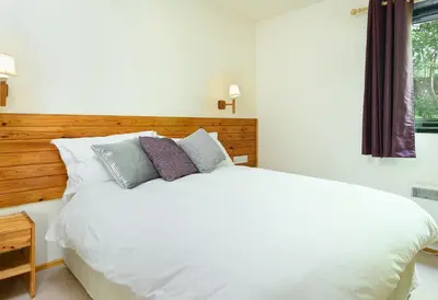 a bedroom with a white bed and a window at Woodlands Hotel & Pine Lodges in Grange Over Sands