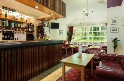 a bar in a pub with a couch and a table at Woodlands Hotel & Pine Lodges in Grange Over Sands