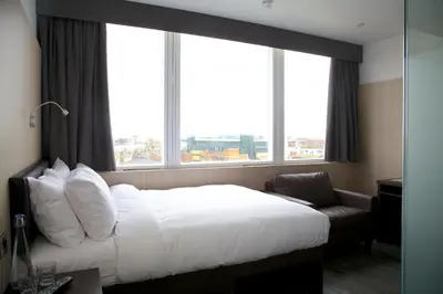 a hotel room with a bed and a chair and windows at The Z Hotel Liverpool in Liverpool