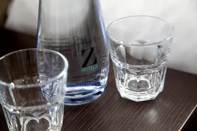 two glasses and a bottle of water on a table at The Z Hotel Liverpool in Liverpool