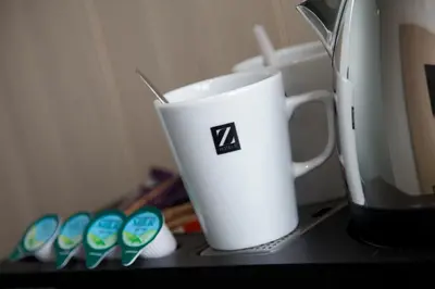 a white cup sitting on a counter next to a coffee maker at The Z Hotel Liverpool in Liverpool