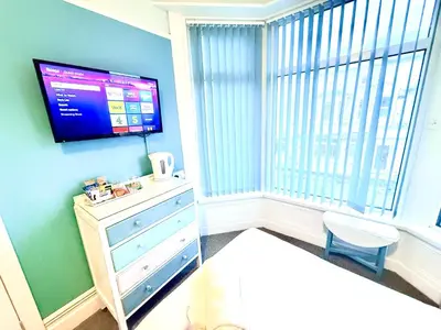a room with a tv on a wall with a dresser at The Gables Hotel by Cherish Lewis Blackpool in Blackpool