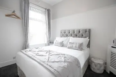 a white bedroom with a large bed and a window at The Gables Hotel by Cherish Lewis Blackpool in Blackpool