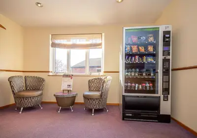 a room with two chairs and a soda machine at Stables Inn, Aintree in Liverpool