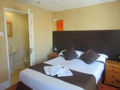 a bedroom with a large white bed and a bathroom at Stuart hotel in Blackpool