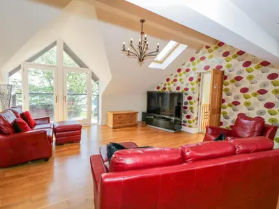 a living room with a red couch and a fireplace at Villa Marina in Barrow in Furness