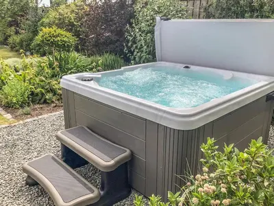 a large hot tub in a garden with two stools at Villa Marina in Barrow in Furness