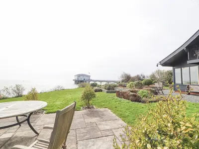 a patio with a table and chairs and the water at Villa Marina in Barrow in Furness