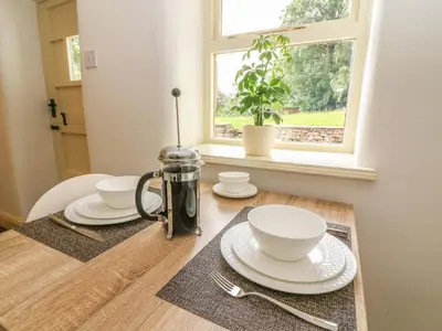 a table with plates and bowls on a table with a window at Spens Farm Cottage in Lancaster