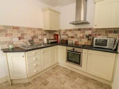 a kitchen with white cabinets and a microwave at Spens Farm Cottage in Lancaster