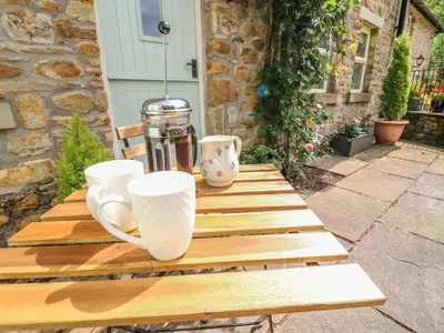 a wooden table with two cups on top of it at Spens Farm Cottage in Lancaster