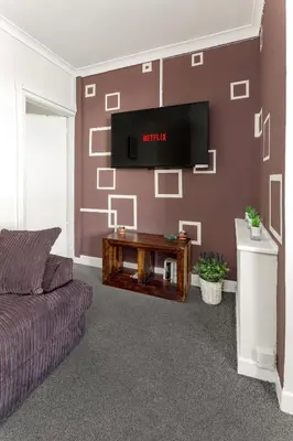 a living room with a couch and a tv on a wall at Cosy Anfield Guesthouse - Close to Stadium & City in Liverpool