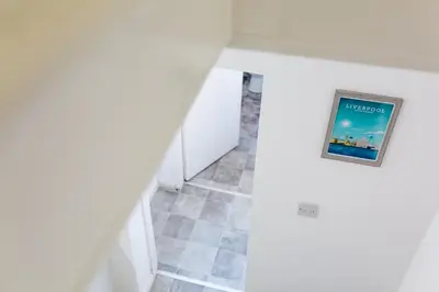 a hallway with white walls and a picture on the wall at Cosy Anfield Guesthouse - Close to Stadium & City in Liverpool