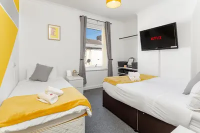 a bedroom with two beds and a flatscreen tv at Cosy Anfield Guesthouse - Close to Stadium & City in Liverpool