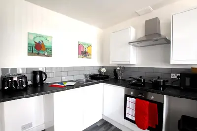 a kitchen with white cabinets and black counter tops at Blackpool Tower Apartments by Blackpool Service Aparttments in Blackpool