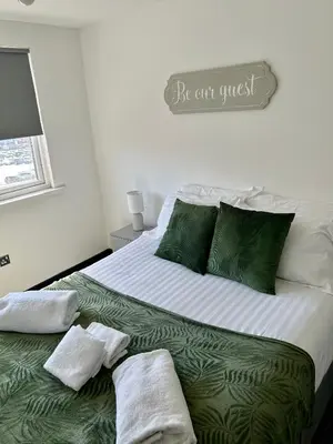 a large bed with green and white sheets and pillows at Blackpool Tower Apartments by Blackpool Service Aparttments in Blackpool