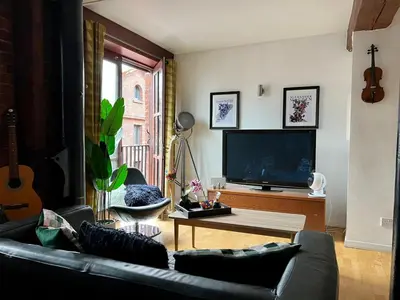 a living room with a couch and a tv at 2 Bed Duplex Penthouse Apartment by Mathew Street Sleeps 6 in Liverpool