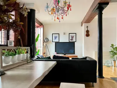 a living room with a black couch and a television at 2 Bed Duplex Penthouse Apartment by Mathew Street Sleeps 6 in Liverpool