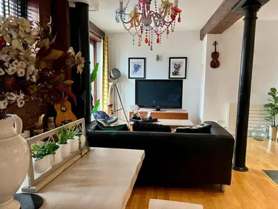 a living room with a black couch and a television at 2 Bed Duplex Penthouse Apartment by Mathew Street Sleeps 6 in Liverpool